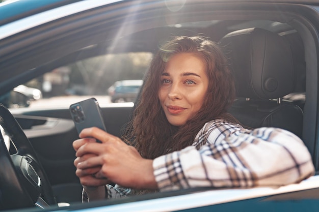 Jeune femme textos sur son smartphone tout en conduisant une voiture