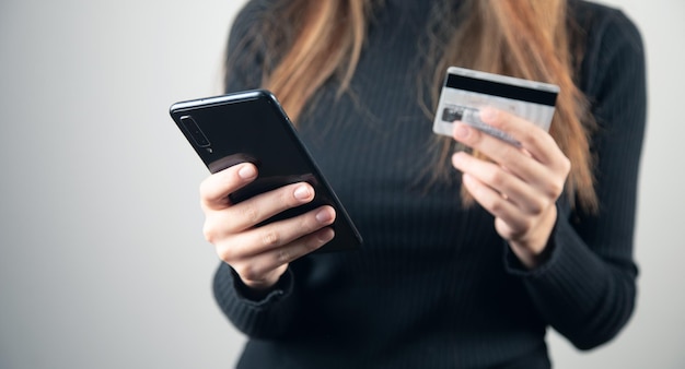 La jeune femme tient la carte de crédit et le téléphone intelligent