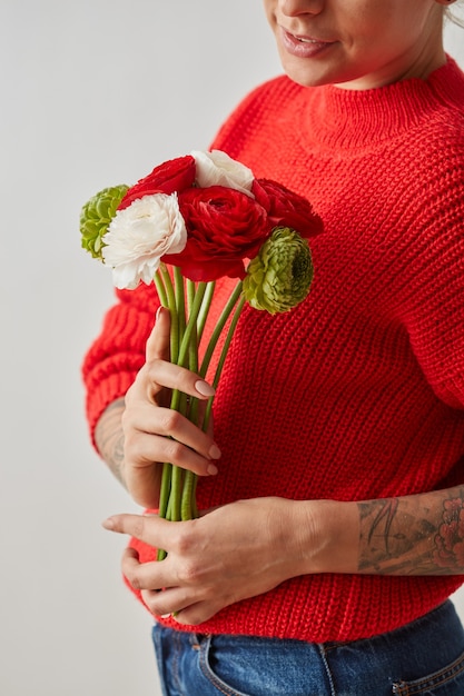 Jeune femme tient dans les mains, des fleurs colorées de renoncule sur fond gris. Comme cadeau pour les vacances