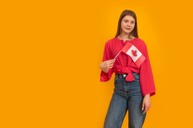 Une jeune femme tient le drapeau du Canada sur fond jaune vif Étudier au Canada Programme d'échange d'étudiants Espace réservé au texte