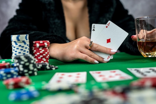 Jeune femme tient des jetons de jeu et des cartes de casino à la table dans une belle robe