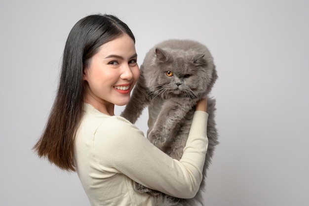 Une jeune femme tient un joli chat jouant avec un chat en studio sur fond blanc