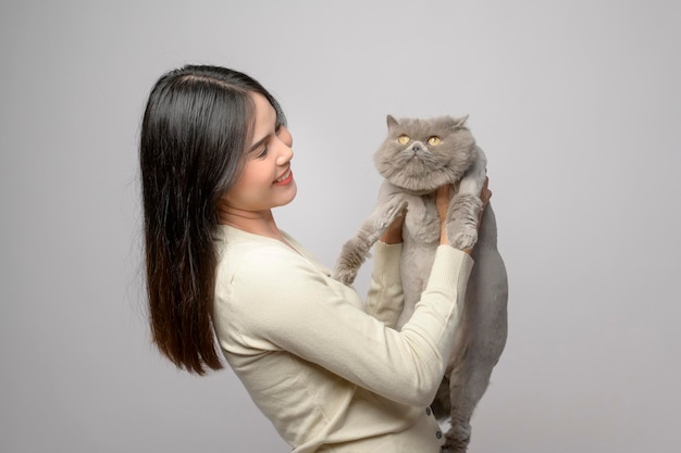 Une jeune femme tient un joli chat jouant avec un chat en studio sur fond blanc