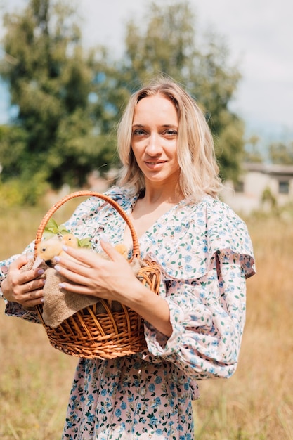 Une jeune femme tient un panier de canetons et sourit