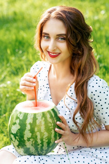 Jeune femme tient une pastèque en plein air