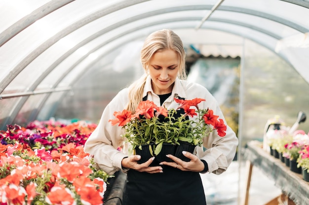 Une jeune femme tient des pots de fleurs dans une serre petite boutique de fleurs du centre de jardinage