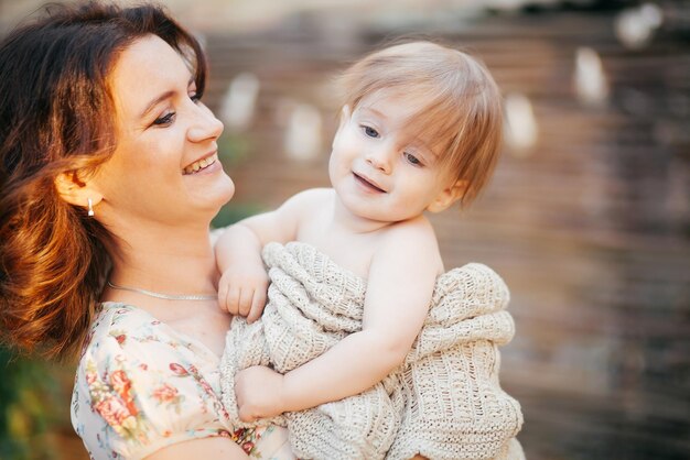 Une jeune femme tient son petit fils dans ses bras dans le jardin au coucher du soleil