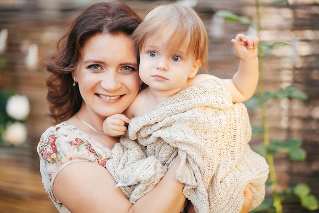 Photo une jeune femme tient son petit fils dans ses bras dans le jardin au coucher du soleil