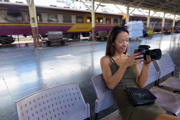 Jeune femme de tourisme assis et à l'aide d'un appareil photo reflex numérique