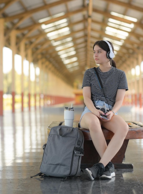 Une jeune femme touriste écoutant de la musique sur un quai de train