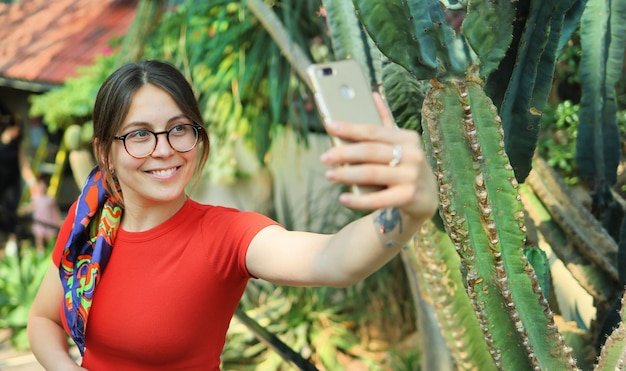 Une jeune femme touriste fait du selfie dans un jardin botanique