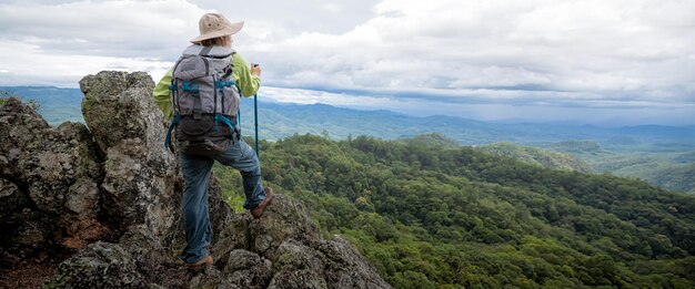 Jeune femme touriste avec sac à dos se reposant sur le rocher et profitant de la vue sur les montagnes