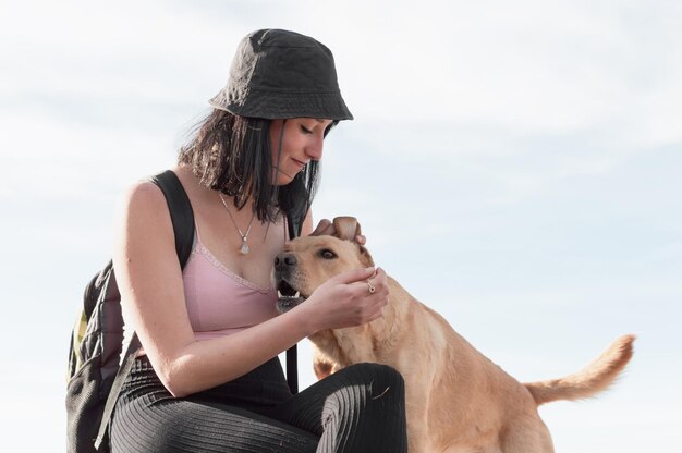 une jeune femme touriste avec son animal de compagnie assise au sommet de la montagne pendant la promenade