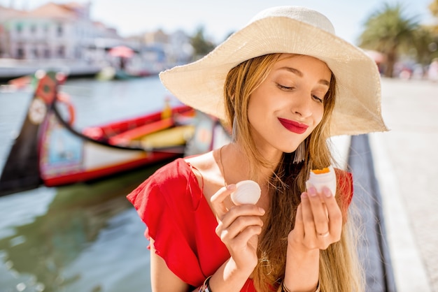 Jeune femme touriste tenant une délicatesse portugaise appelée Ovos Moles à base de jaunes d'œufs et de sucre sur le fond du canal de l'eau dans la ville d'Aveiro, Portugal