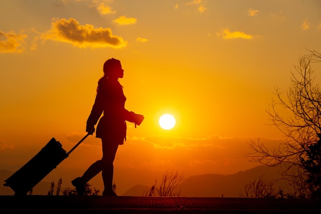 Jeune femme touriste transportant des bagages au coucher du soleil