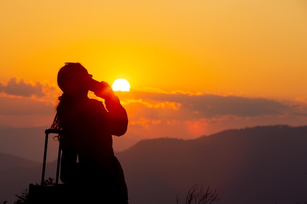 Jeune femme touriste transportant des bagages au coucher du soleil