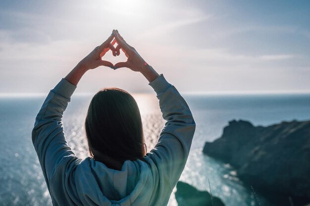 Une jeune femme touristique profitant du coucher de soleil sur le paysage de montagne de la mer alors qu'elle était assise en plein air pour le yoga pour femmes