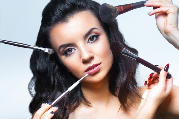 Jeune femme avec toutes sortes d'outils de maquillage