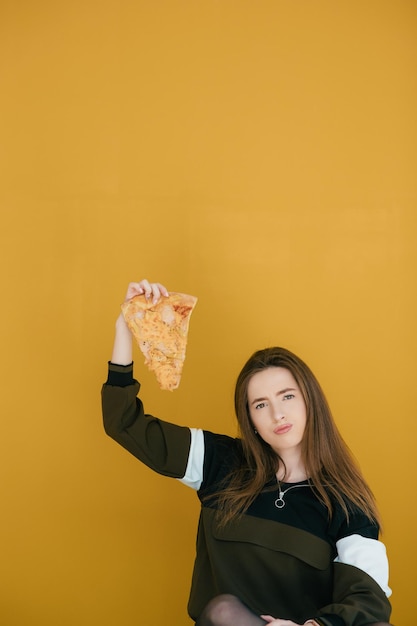 Jeune femme avec une tranche de délicieuse pizza sur un fond de couleur