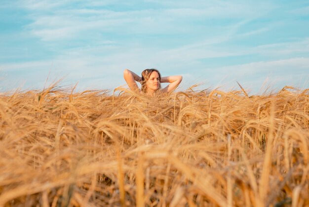 Jeune femme tranquille à l'intérieur du champ de blé d'or en été méditant dans la nature