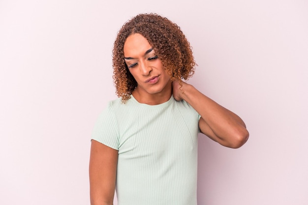 Jeune femme transsexuelle latine isolée sur fond rose ayant une douleur au cou due au stress, massant et touchant avec la main.