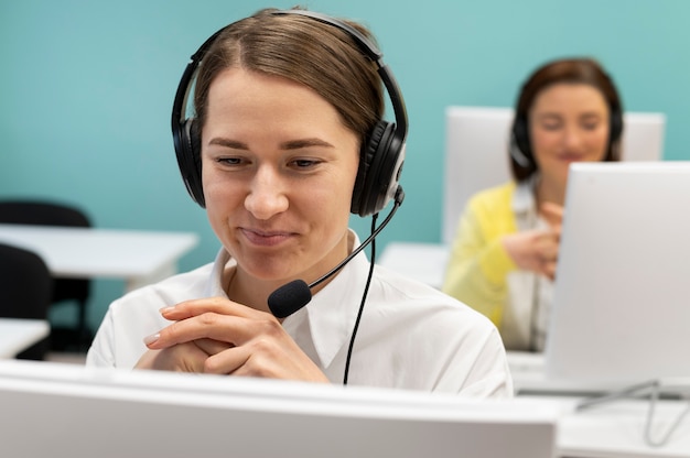 Jeune femme travaillant au bureau du centre d'appels avec un casque et un ordinateur