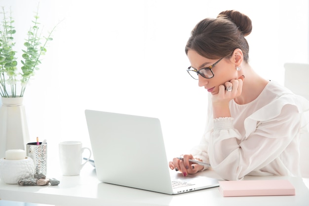 Jeune femme travaillant à un bureau avec un ordinateur portable dans un bureau. Entreprise féminine, travail à distance.