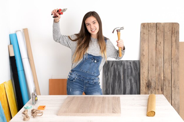 Jeune femme travaillant dans un atelier d'artisanat avec divers outils et matériaux heureux et amusant