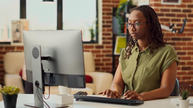 Jeune femme travaillant à distance depuis son domicile sur le travail de l'entreprise, effectuant des tâches comptables et vérifiant le rapport en ligne. Consultation des données Internet et envoi d'e-mails au responsable du réseau marketing.