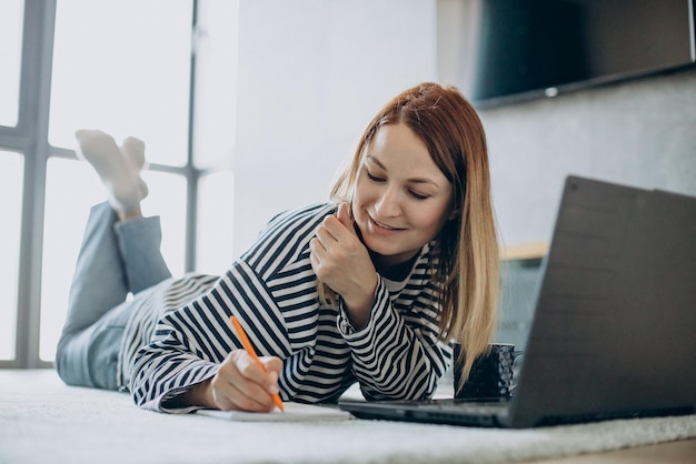 Jeune femme travaillant et étudiant sur son ordinateur portable à la maison