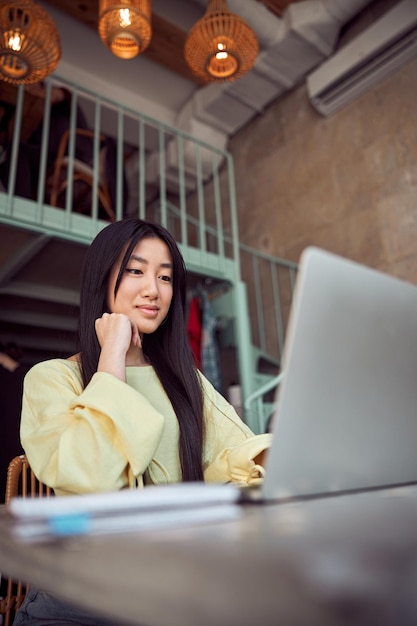 Jeune femme travaillant joyeusement sur un ordinateur portable à l'intérieur