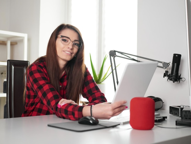 Jeune femme travaillant à la maison sur un ordinateur de bureau et une tablette numérique