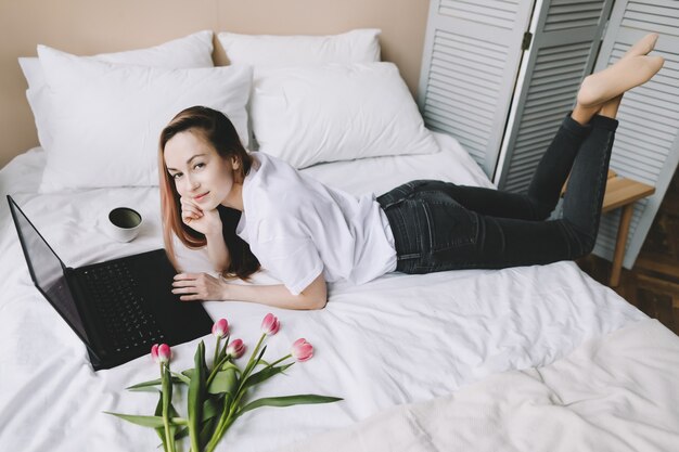 Jeune femme travaillant sur ordinateur portable au lit Travail à domicile concept de quarantaine