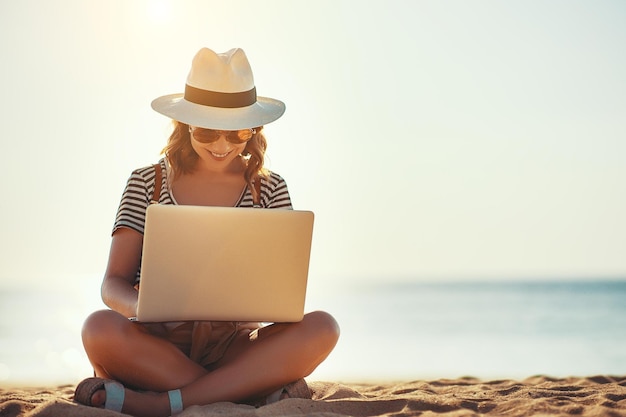 Jeune femme travaillant avec un ordinateur portable sur la nature en plage d'été