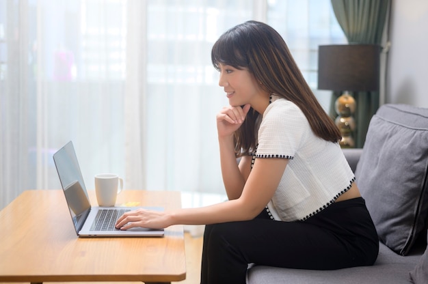 Une jeune femme travaillant avec son ordinateur portable et prenant une tasse de café, un style de vie et un concept d'entreprise