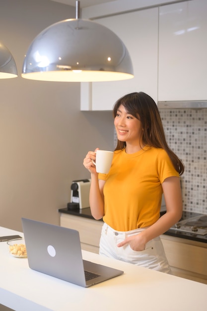 Une jeune femme travaillant avec son ordinateur portable et prenant une tasse de café, un style de vie et un concept d'entreprise