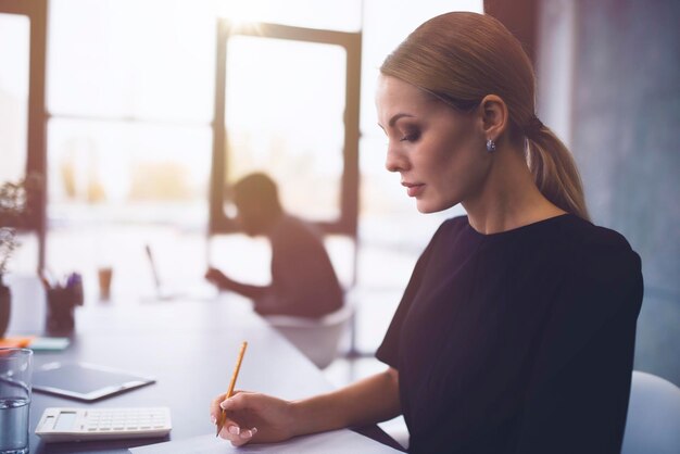 Photo une jeune femme travaillant sur une table.