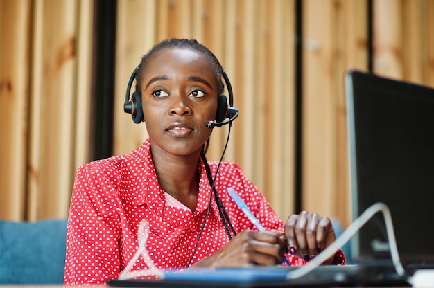 Une jeune femme travaille dans un opérateur de centre d'appels et un agent du service client portant des casques micro travaillant sur un ordinateur portable