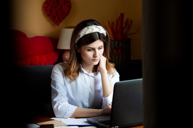 La jeune femme travaille à l'ordinateur dans un café