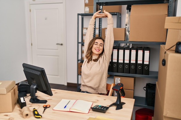 Jeune femme travailleuse d'une entreprise de commerce électronique qui s'étend des bras au bureau