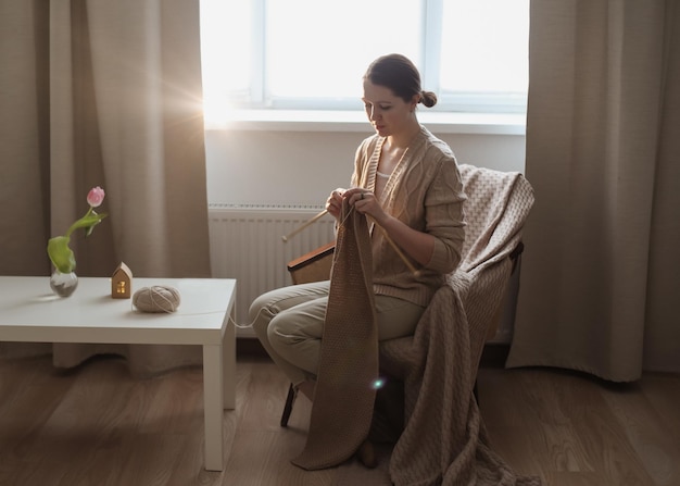 Jeune femme tricotant dans une pièce confortable à la maison