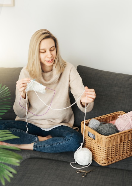 Une jeune femme tricotant une écharpe chaude à l'intérieur