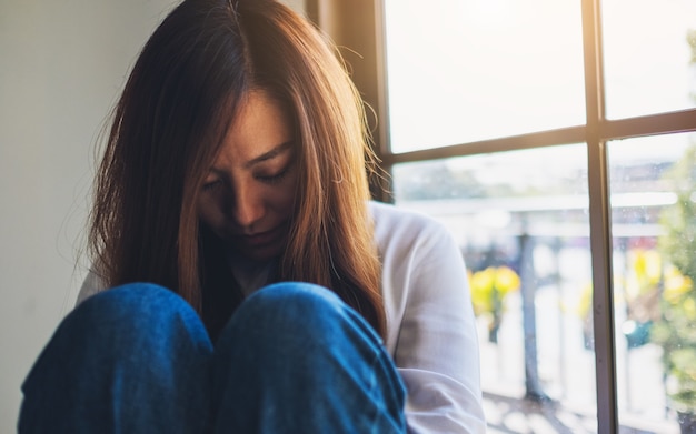 Une jeune femme triste assise seule dans la chambre