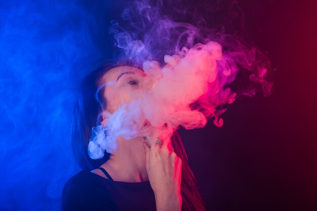 Photo jeune femme en tshirt noir vaping en néon rouge et bleu.