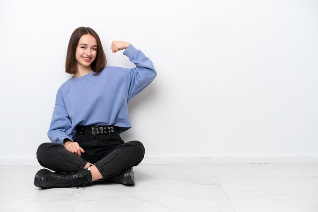 Jeune femme ukrainienne assise sur le sol isolé sur fond blanc faisant un geste fort