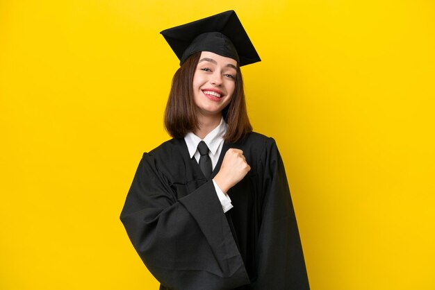 Jeune femme ukrainienne diplômée universitaire isolée sur fond jaune célébrant une victoire