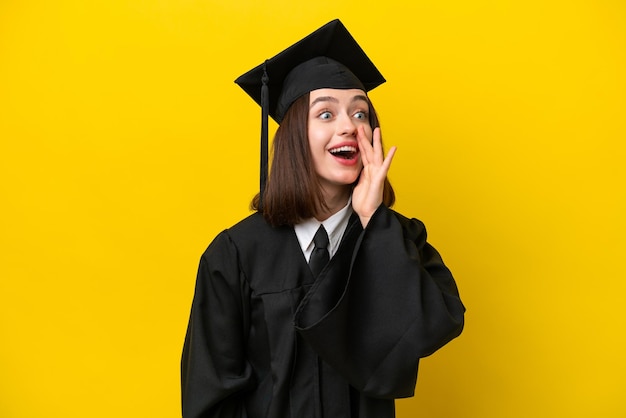 Jeune femme ukrainienne diplômée universitaire isolée sur fond jaune criant avec la bouche grande ouverte sur le côté