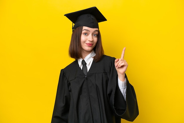 Jeune femme ukrainienne diplômée universitaire isolée sur fond jaune pointant avec l'index une excellente idée