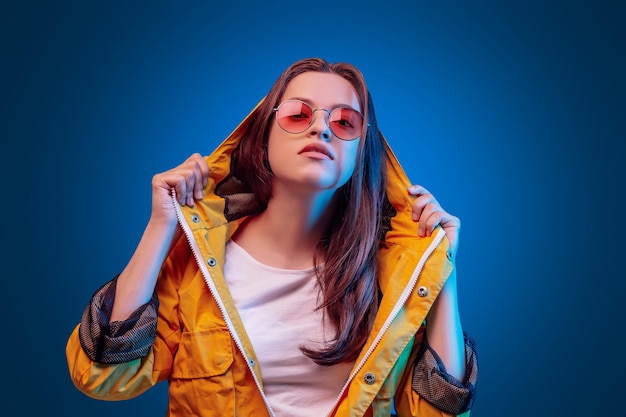 Jeune femme ukrainienne en imperméable jaune et lunettes rondes en fond bleu