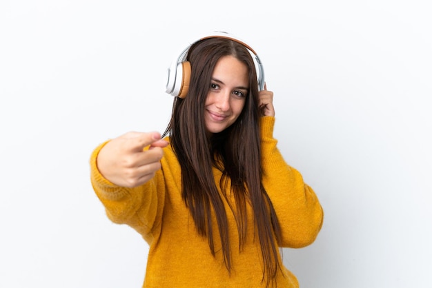 Jeune femme ukrainienne isolée sur fond blanc écoutant de la musique et pointant vers l'avant